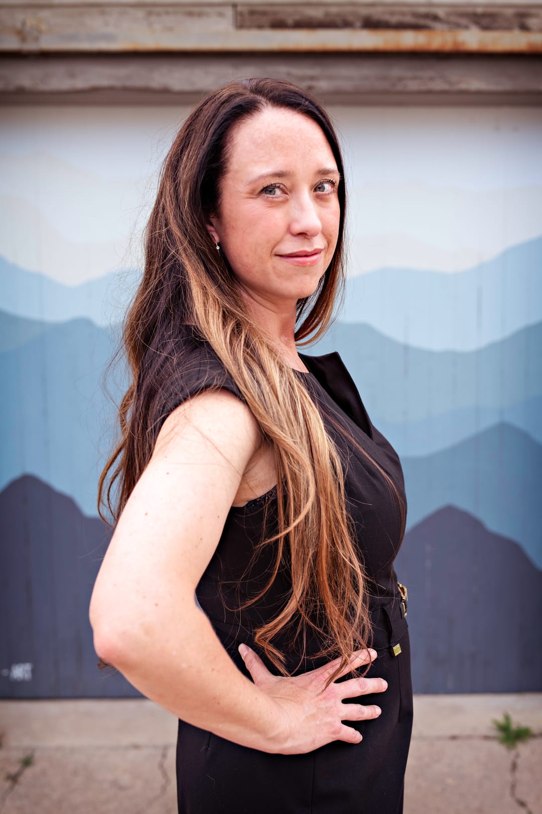Stephanie Drobny in front of a painted mountain mural, looking at the camera