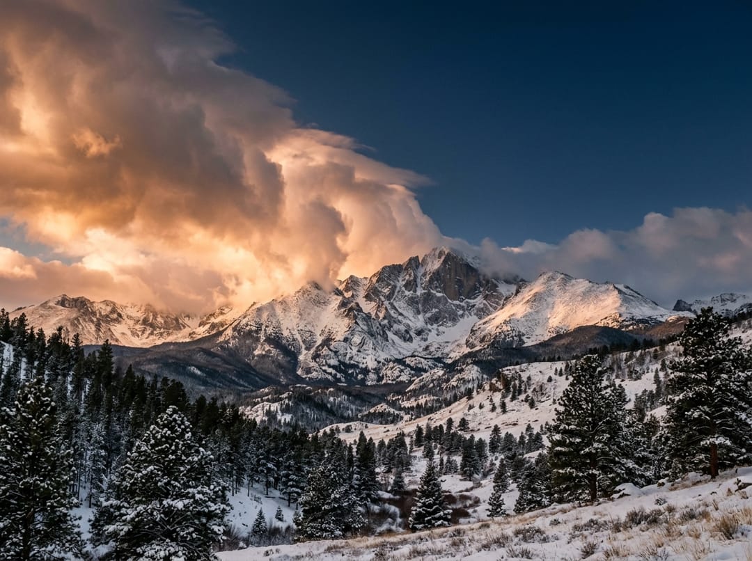 A snow-covered summit at sunset as a storm breaks apart and clears