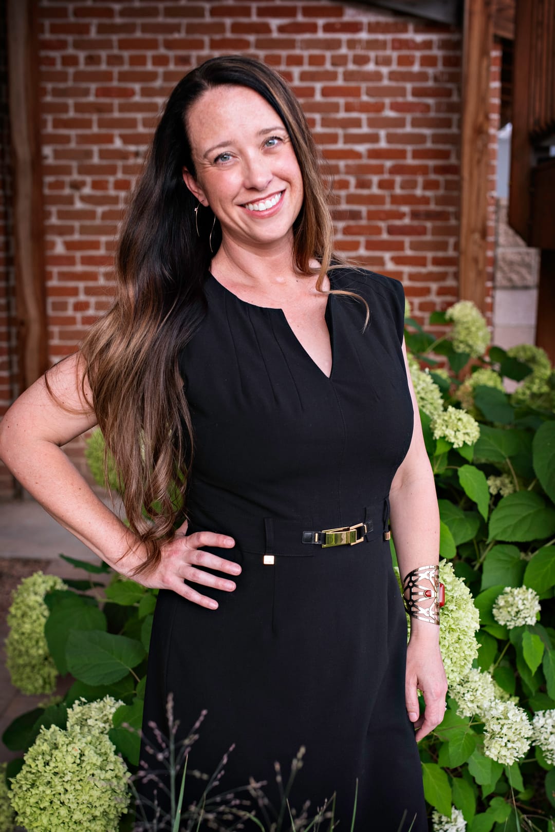 Stephanie Drobny beside white hydrangeas against a tan brick wall