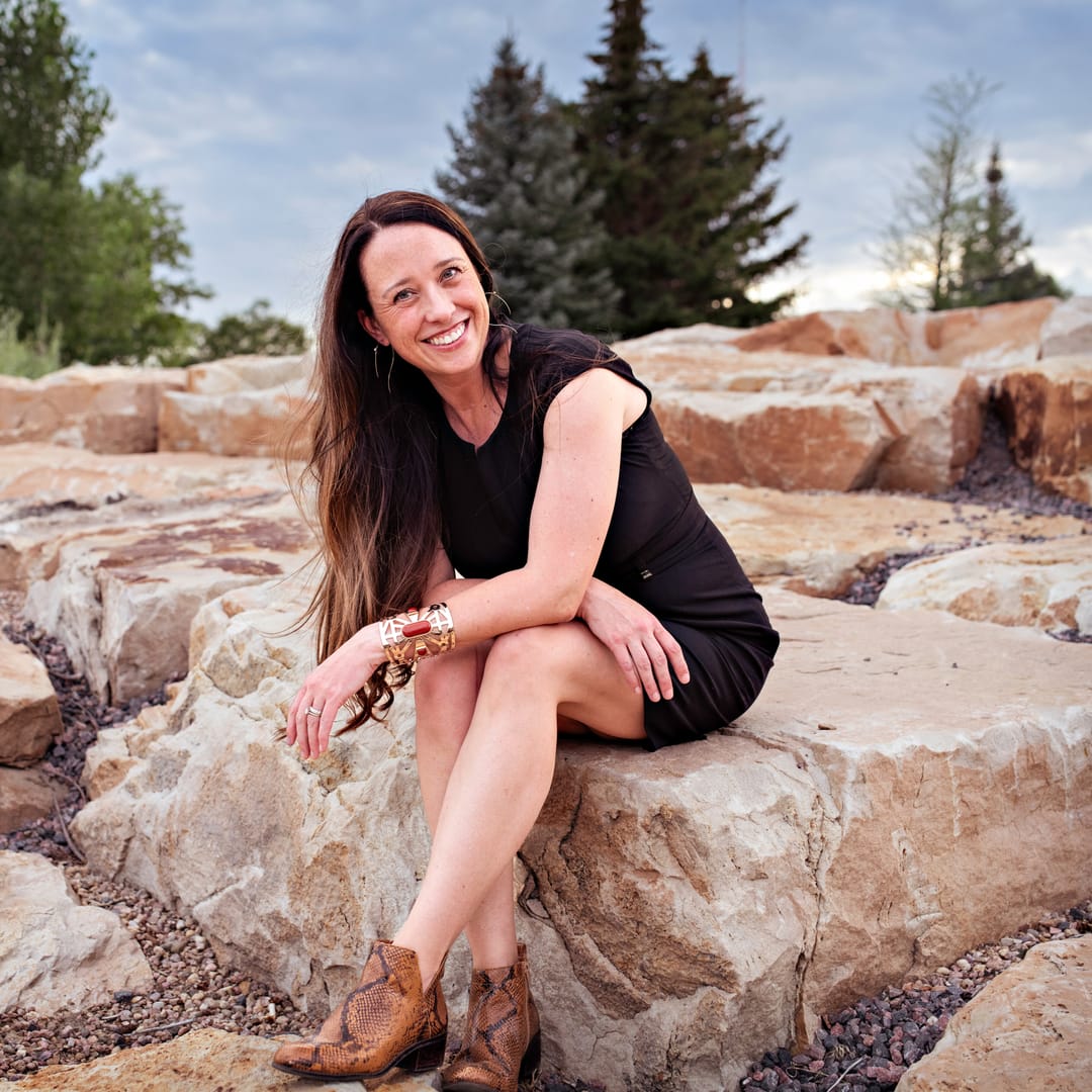 Stephanie Drobny seated on sandstone rocks, smiling